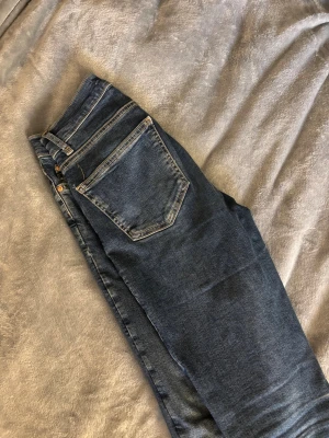 Blå raka jeans med rå kant - Snygga blå jeans med rak passform och klassiska fickor. Jeansen har en rå, något fransig kant nertill för en trendig look. Perfekta till sneakers eller boots. Materialet är denim i bomull med lite stretch för extra komfort. Säljer förnyat dom är förstora. 