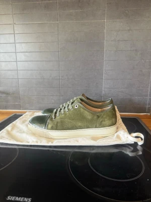 Olivgröna sneakers i mocka och läder - Snygga olivgröna sneakers med ovandel i mocka och detaljer i blankt läder på tån och hälen. Skorna har vita sulor och matchande olivgröna snören. Skorna är i 7/10 skulle jag säga. De är väldigt fina dock pga defekterna på captoen säljer jag billigare. Pris ej hugget i sten🤝