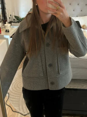 Grå kort kappa från Kappahl i stl S - Snygg grå kappa. Perfekt att slänga på sig över en hoodie eller t-shirt. Kör för ca 500kr, inga defekter och är som nu, tillkommer även en extra knapp. 