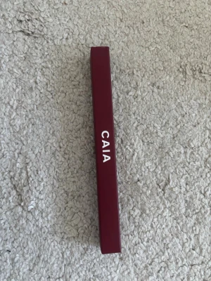 Oöppnad CAIA läppenna Ruby Plum - Snygg läppenna från CAIA i färgen Ruby Plum. Pennan har en djup plommonröd nyans och kommer i en stilren, vinröd förpackning. Perfekt för att definiera och framhäva läpparna med precision. Nypris: 195kr!