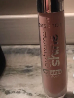 Essence Extreme Shine Volume Lipgloss - Säljer ett Essence Extreme Shine Volume Lipgloss i en nude/ljusrosa nyans. Läppglanset kommer i en genomskinlig tub med silverfärgat lock och har en glansig finish som ger volym till läpparna. Perfekt för dig som vill ha extra glans och en naturlig look.
