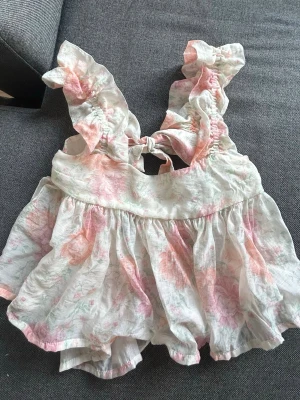 Blommig topp med volang och rosett - Supersöt topp med volangärmar och rosett i ryggen. Luftigt material som är perfekt för sommaren💕