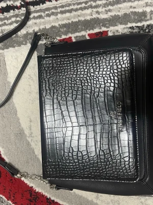 Svart axelväska från Anna Field - Snygg svart axelväska från Anna Field med croco-mönstrad framsida och silverfärgade detaljer. Pris går att diskutera! 