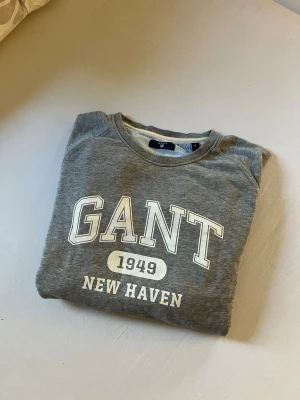 Grå sweatshirt från GANT - Snygg grå sweatshirt från GANT med tryck 'GANT 1949 NEW HAVEN' på bröstet.💕