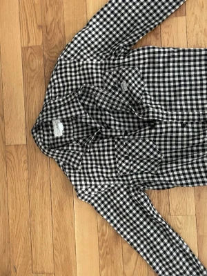Rutig skjorta från Ralph Lauren - Snygg svartvit rutig skjorta från Denim & Supply Ralph Lauren. Skjortan är i 100% bomull och har klassisk krage, knäppning framtill och två bröstfickor. Perfekt för en avslappnad och trendig look.