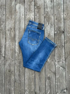 Replay anbass jeans - slim fit - w32 - Snygga blå jeans från replay med klassisk femficksdesign och tydliga kontrastsömmar. Jeansen har en slim passform och är tillverkade i denim med lätt slitna detaljer. Perfekta för en avslappnad och trendig look.