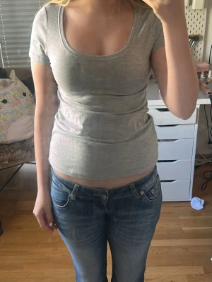 Grå basic t-shirt med rund hals - Enkel och stilren grå t-shirt med rundad urringning och korta ärmar. Perfekt att matcha med jeans eller kjol för en avslappnad look. Mjuk och skön mot huden.