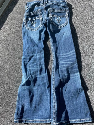 Blå bootcut jeans från Gina tricot  med broderade fickor - Fina bootcut jeans från Gina tricot i storlek 140,  fint skick!