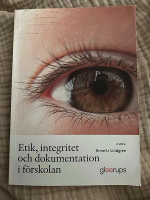Etik, integritet och dokumentation - Kursbok i pedagogik: 'Etik, integritet och dokumentation i förskolan' av Anne-Li Lindgren. Andra upplagan. Boken har ett omslag med närbild på ett öga och är tryckt i mjukt papper. Perfekt för dig som pluggar till förskollärare eller jobbar inom förskolan.