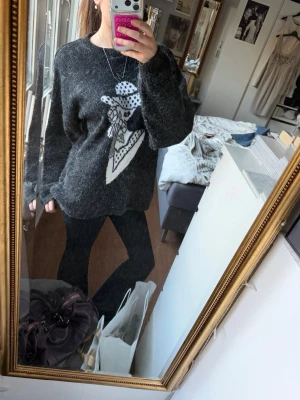 Svart stickad tröja med motiv! - Mysig svart stickad tröja med ett stort vitt och svart motiv framtill som föreställer en tecknad kvinna med hatt. Tröjan har rund halsringning och långa ärmar. Perfekt för dig som gillar unika och coola plagg! Gör din look mycket coolare och unikare samtidigt💕
