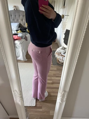Rosa juicy byxor - Säljer ett par ljusrosa mjukisbyxor med bootcut-modell och låg midja. Byxorna har fickor både fram och bak samt dragkedjedetaljer framtill. De är från Juicy Couture!🌸🌺