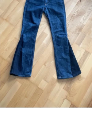 Acne jeans - Säljer ett par blå jeans från Acne med utsvängda ben och klassisk femficksmodell. Jeansen har en snygg mörk tvätt och detaljer i kontrastsömmar.