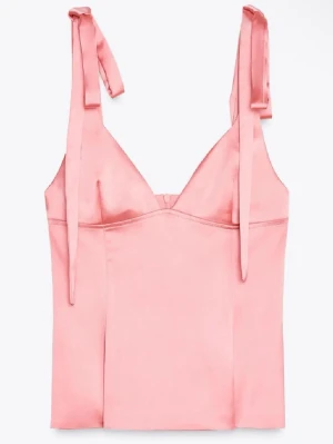 Rosa satinlinnetopp med knytband - Supersöt rosa linnetopp i satin med smala axelband som knyts på axlarna. Toppen har v-ringning och en lätt figurnära passform som ger en feminin siluett. Perfekt att styla med jeans eller kjol för en trendig look.