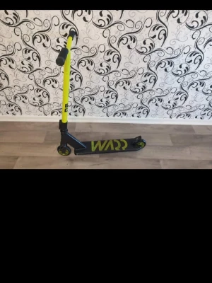 Svart och gul sparkcykel WARP - Säljer en cool sparkcykel från WARP i svart med gula detaljer och handtag. Styret är gult och har svarta handtag, medan fotplattan är svart med gul WARP-logga. Perfekt för att cruisa runt eller göra tricks i skateparken.