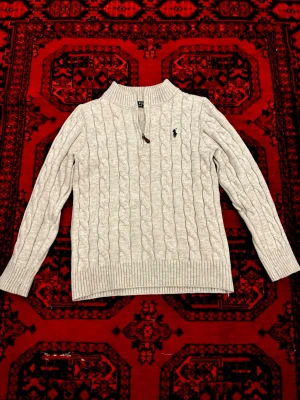Ljusgrå kabelstickad tröja Polo Ralph Lauren - Snygg Ralph Lauren stickad quarter zip som jag nu tänker sälja, skicket är perfekt utan några defekter, det står L men sitter som EU S då den har krympt efter varmtvätt och inte passar mig längre. Perfekt får våren och kyliga sommarkvällar. Pris går att diskutera! 💯