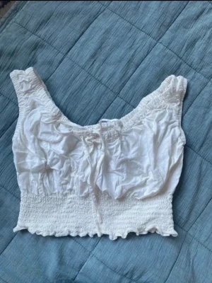 Vintage Vit croppad coquette topp från John Galt - Söt vit croppad topp från John Galt med smockad midja och volangkant. Toppen har breda axelband, knytning framtill. Passar XXS/XS EU32. Pris kan diskuteras