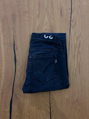 Dondup george jeans - Snygga mörkblå jeans med en unik ögon-detalj i linningen. Klassisk femficksmodell med raka ben och diskreta sömmar. Perfekta för dig som vill ha något lite annorlunda i garderoben.