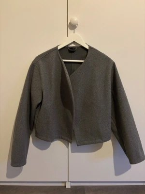 Grå kort kappa från ginatricot  - Säljer en kort grå kappa från ginatricot som passar perfekt till höst och vår. Den är i storlek S och i mycket bra skick då den endast använts ett fåtal gånger. Säljer då den inte längre faller mig o smaken. Hör gärna av er vid frågor och funderingar eller om ni vill ha fler bilder😊🫶🏼