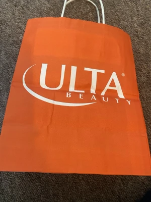 Orange shoppingväska från Ulta Beauty - Snygg orange shoppingväska från Ulta Beauty med vitt tryck och texten 'the possibilities are beautiful'. Väskan har vita handtag och är tillverkad i ett tåligt material, perfekt för shopping eller att bära med sig grejer.