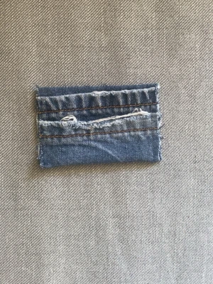 Blå denim plånbok med slitna detaljer - Unik plånbok sydd av återvunnet blått denimtyg med råa kanter och slitna detaljer. Plånboken har flera kortfack och en cool, avslappnad look. Perfekt för dig som gillar streetstyle och vill ha något annorlunda. Plånboken är gjord av vårat uf företag deni_mdesign