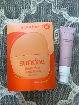 Sundae Body Mist Mood Board samt Hickap primer - Fräsch face mist från Sundae i en rundad, persikofärgad flaska. Doft av kamomill och aloe vera. Perfekt för att återfukta och fräscha upp huden under dagen. Snygg och modern design som passar i väskan. Primer från Hickap.