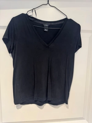 Svart v-ringad t-shirt från Lindex - En svart t-shirt från Lindex med v-ringning och korta ärmar. Enkel och stilren modell som passar till det mesta. Tillverkad i mjuk bomull för en skön känsla hela dagen.