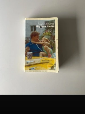 Mig äger ingen av Åsa Linderborg - En gripande pocketbok av Åsa Linderborg, 'Mig äger ingen', med färgstarkt omslag som visar en pappa och dotter. Boken är tryckt på vitt papper och har ett mjukt omslag med inslag av gult och blått. Perfekt för dig som gillar svensk samtidslitteratur.