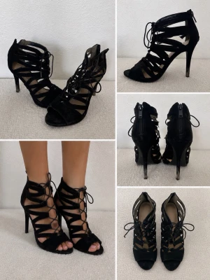 Svarta mocka pumps med snörning - Snygga svarta pumps från Gardenia i mocka med höga klackar och öppen tå. Skorna har coola utskurna detaljer och snörning framtill som ger en edgy vibe. Perfekta för dig som gillar att sticka ut med din stil.