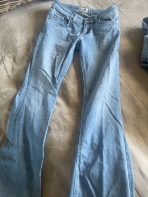 Ljusblå bootcut jeans från 157 - Säljer ett par ljusblå bootcut jeans från 157 med klassisk femficksdesign och normalhög midja. Jeansen har utsvängda ben och är tillverkade i mjuk denim med lite stretch för extra komfort. Perfekta för en avslappnad och trendig look.
