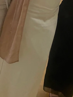 Bal ljus klänning i satin - Elegant långklänning i ljus champagnefärg med långärmad design. Klänningen har en rak och enkel passform och är tillverkad i ett glansigt satinmaterial som ger en lyxig känsla. Använde 1 gång 