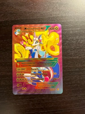 Pokémonkort M Shining Primarina EX - Säljer ett färgstarkt och glittrigt Pokémonkort: M Shining Primarina EX. Kortet har en cool design med mycket gult, rosa och blått, samt holografisk yta. Perfekt för samlare eller dig som vill boosta din lek med en unik och snygg EX-kort.