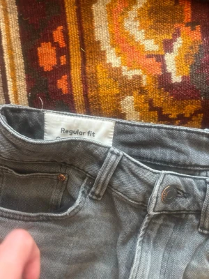 Gråa regular fit jeans från HM - Säljer ett par gråa jeans från Cubus i regular fit-modell. Jeansen har klassisk femficksdesign, knappgylf och bälteshällor. Perfekta för en avslappnad och stilren look. Materialet är mjukt denim som ger en skön känsla hela dagen.