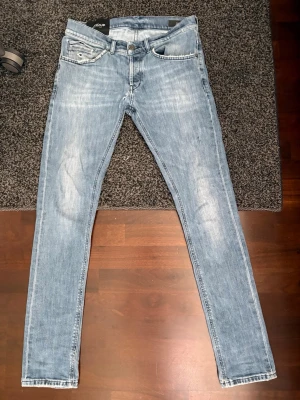 Ljusblå slim fit jeans från J.Lindeberg - Snygga ljusblå slim fit jeans från dondup med klassisk femficksdesign och diskreta slitningar. Jeansen har knappar  i midjan samt detaljerade bakfickor. Perfekta för en trendig och avslappnad stil. DEFEKTA, finns ett hål under gylfen som bör sys ihop där av det billiga priset (Sista bilden) köptes på NK för ett år sedan och har använts en del men fortfarande fina utöver hålet😊 mått eller fler bilder fås vid förfrågan. Mvh//Hugo