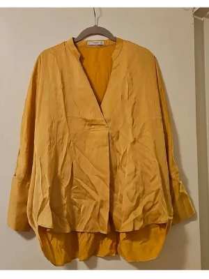 Oversized gul skjorta från Uniqlo U - Säljer en oversized skjorta från Uniqlo U i en snygg gul färg. Skjortan har lång ärm med knappar vid manschetten, v-ringad hals och är tillverkad i ett mjukt material som ger ett avslappnat intryck. Perfekt för dig som gillar en loose fit och stilren design.