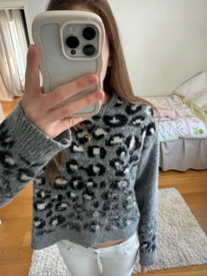 Grå leopardmönstrad stickad tröja - Säljer en super snygg grå stickad tröja från ONLY med leopardmönster i svart och vitt. Tröjan har rund halsringning, långa ärmar och ribbade muddar. Säljer bara för att den inte kommer till användning!