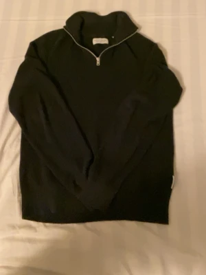 Svart stickad halvzip-tröja  - Säljer en svart stickad tröja med halvzip och hög krage. Nypris 800 Tröjan har långa ärmar och ribbade muddar vid ärmslut och nederkant. Perfekt för lager på lager och enkel att matcha med olika outfits, använt den 10 gånger typ.