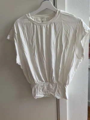 Vit croppad topp - säljer denna jätte söta topp ifrån halara! den här ett band längst ner så man kan justera hur lång man vill att toppen ska vara, bandet är också tajt så toppen är fin att styla med ett par low waist jeans! använd ca 3 gånger! 