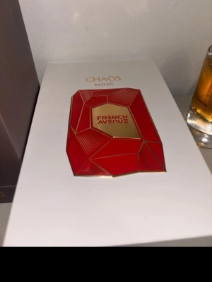 French Avenue Chaos Extrait Parfym - Lyxig parfym från French Avenue i modellen Chaos Extrait. Flaskan är djup röd med geometrisk design och gulddetaljer, samt ett elegant guldfärgat lock. Kommer i en snygg vit och röd förpackning med guldtext. Perfekt för dig som gillar exklusiva dofter.