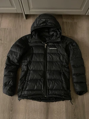 Svart dunjacka Peak Performance XS - Säljer en svart dunjacka från Peak Performance i storlek XS. Jackan har två lagnings klappar syns på dom två sista bilderna, klassisk puffer-modell med broderad logga på bröstet hör av er om det är några frågor!!