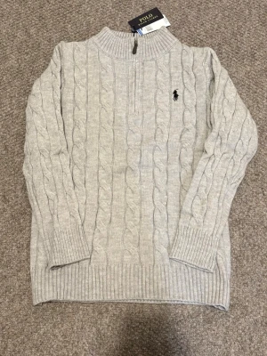Polo ralph lauren quarter zip - Brand new Polo Ralph Lauren quarter zip sweater for sale. Perfect for autumn and winter wear. Classic black shade with the iconic embroidered logo on the chest  🔹 Brand: Polo Ralph Lauren 🔹 Color: grey 🔹 Model: Cable knit, long-sleeved 🔹 Condition: Brand new with tags ✨ 🔹 Size: L  Perfect for a clean, smart, and polished look 👌 📦 Fast shipping | 💬 Feel free to ask for more information
