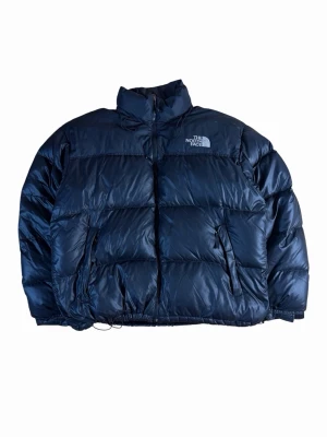 Svart dunjacka från The North Face  - Bra vintage condition. Finns en liten lagning se bild, inget som syns dock. Mått: bröstvidd - 67 cm, längd - 70cm, armlängd - 63 cm. 