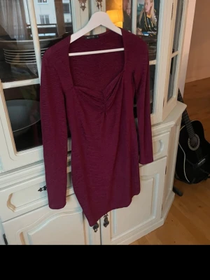 Vinröd långärmad klänning NLY ONE - Säljer en vinröd långärmad klänning från NLY ONE. Klänningen har en snygg rynkad detalj vid bysten och en smickrande fyrkantig urringning. Materialet är stretchigt och känns bekvämt mot huden. 