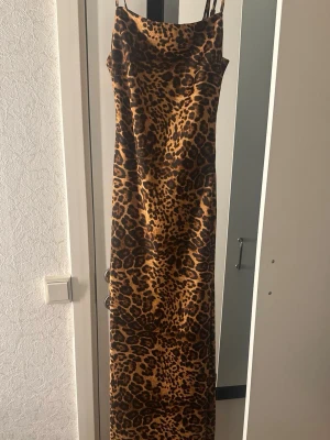 Leopardmönstrad långklänning DW Noelle - Snygg långklänning från bikbok med leopardmönster. Klänningen har smala axelband och en rak, figurnära passform. Perfekt för dig som vill sticka ut med ett djurmönster. Materialet känns mjukt och följsamt.