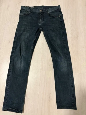 Mörkblå jeans från J.Lindeberg - Snygga mörkblå jeans från J.Lindeberg med klassisk femficksmodell och raka ben. Jeansen har diskreta slitningar och är tillverkade i ett mjukt denimtyg som sitter skönt. Perfekta för en avslappnad och trendig look. 30/32