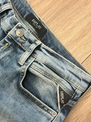 Slim fit jeans från Replay - Säljer ett par klassiska blå jeans från Replay med raka ben och femficksmodell. Jeansen har en ljus tvätt och tydliga sömmar, samt Replay-lapp bak i midjan. Perfekta för en avslappnad och trendig stil.