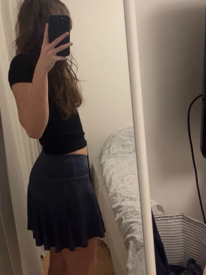 Tenniskjol med inbyggda shorts - En väldigt snygg och praktisk kjol som passar perfekt till träning. Den är lite blå grå i färgen och har en fin omlott detalj i midjan. Den har även inbyggda shorts som även har fickor.🥰