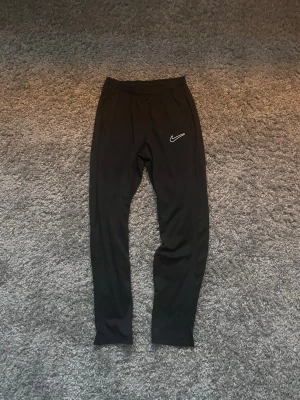 Svarta träningsbyxor från Nike - Säljer ett par svarta träningsbyxor från Nike i storlek 158-170cm och säljs för 150kr!