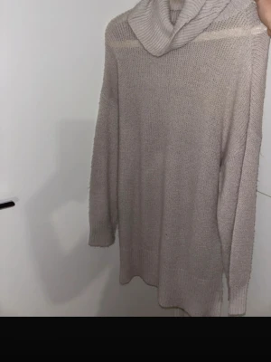 Beige stickad polotröja - Mysig beige stickad polotröja med lång ärm och avslappnad passform. Tröjan har en bred polokrage och ribbstickade muddar vid ärmslut och nederkant. Perfekt för lager på lager och höstmys.