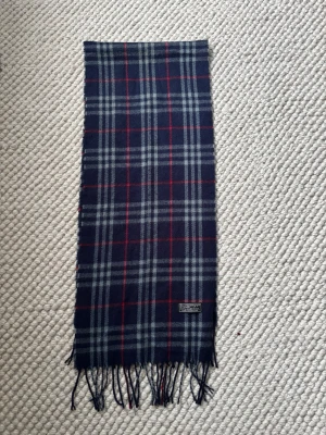 Burberry Halsduk - Säljer denna halsduken från Burberry! Riktigt snygg med ett randigt mönster och säljs för 299kr! Snabb affär= bättre pris!