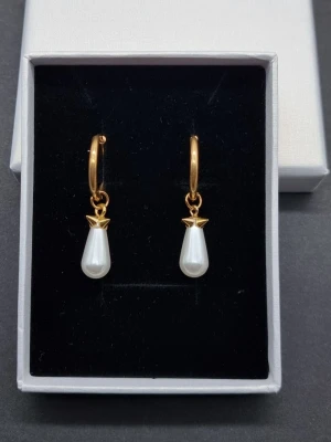 Handgjorda örhängen med pärldroppar  - Stilrena örhängen lãngd-3,7cm. Material-rostfritt stål. Vid köp ingår två  extra berlocker som kan bytas då själva hänget ar ömtåligt och känsligt för stötar. Örhängena påminner om Maria Nilsdotter.